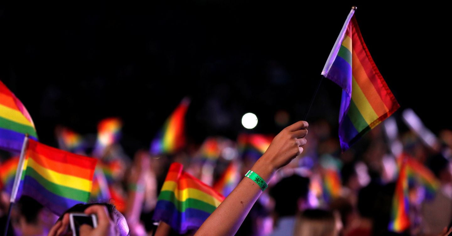 Hands in the air holding rainbow flag